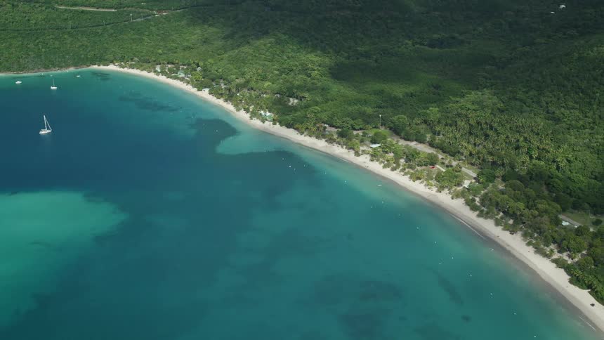 Aerial panorama of an archipelago with a turquoise blue beach and lush vegetation beneath mountains