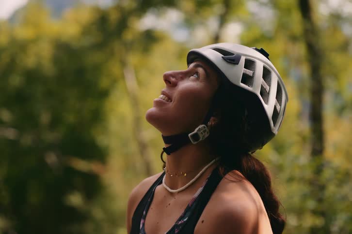 Portrait of a young woman with a protective helmet looking up in the midst of a forest