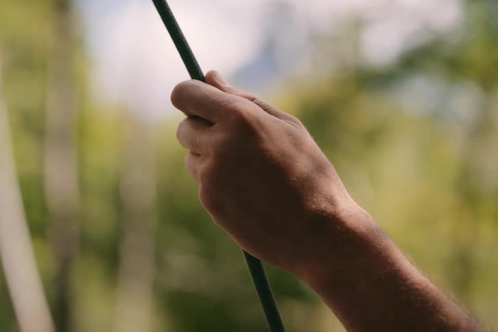 Man pulls on rope while outdoors during a sunny day