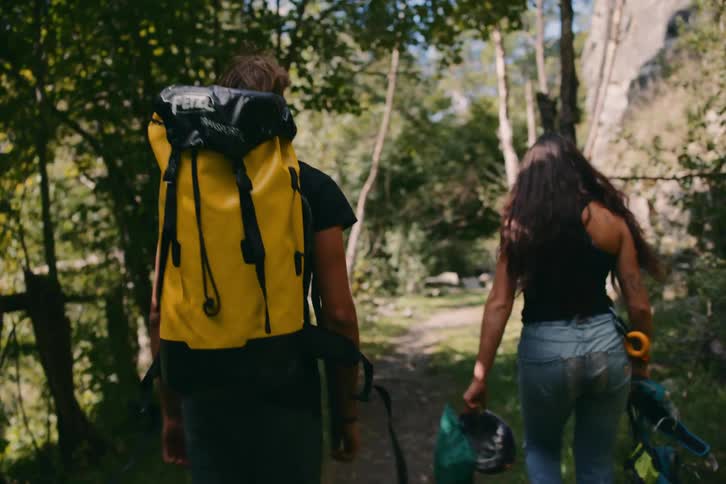 Two people walk outdoors on treelined trail