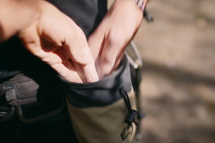 A mountain climber chalks his hands from a pouch
