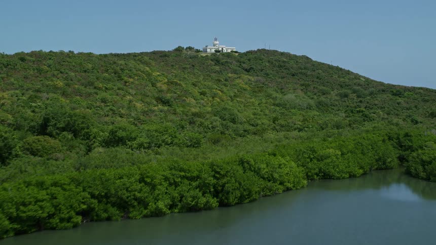 A big white mansion on top of a hill on an island surrounded by an ocean