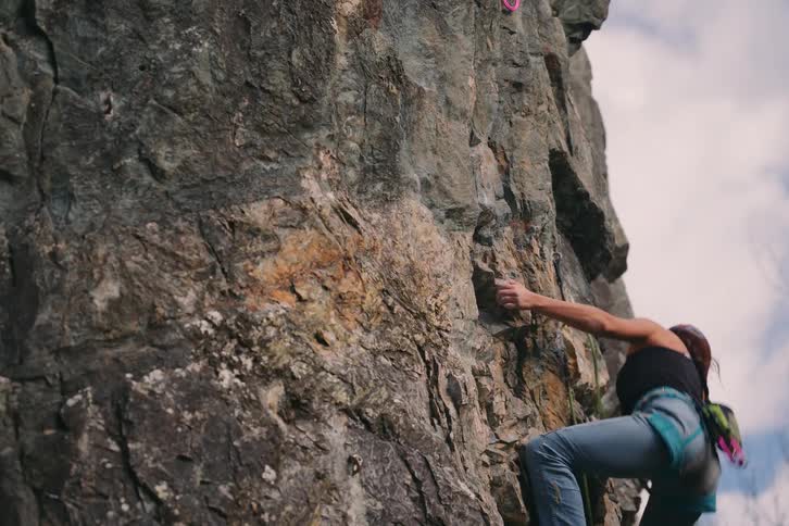 A woman climbing a rocky mountain wearing safety equipment