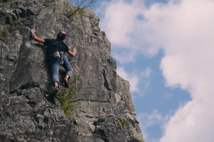 Woman climbing a rocky mountainous terrain during the day