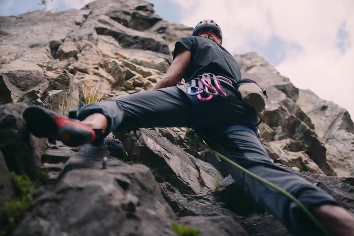 A man is using equipment and climbing a rock