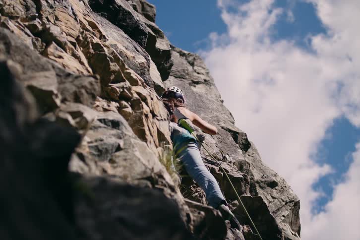 A woman is on her back and climbing a stone mountain