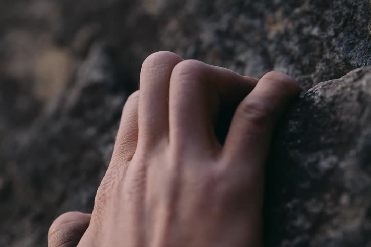 A persons hand tightly gripping a rock