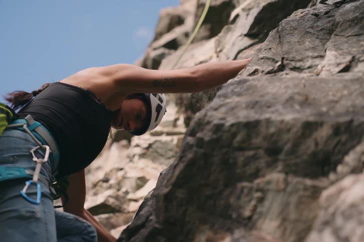 Woman climbing a rocky surface in the midst of a mountain