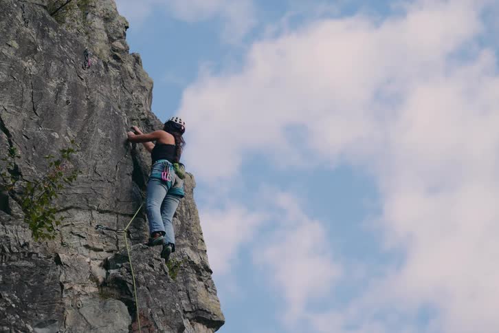 A rock climber is ascending a steep rugged cliff