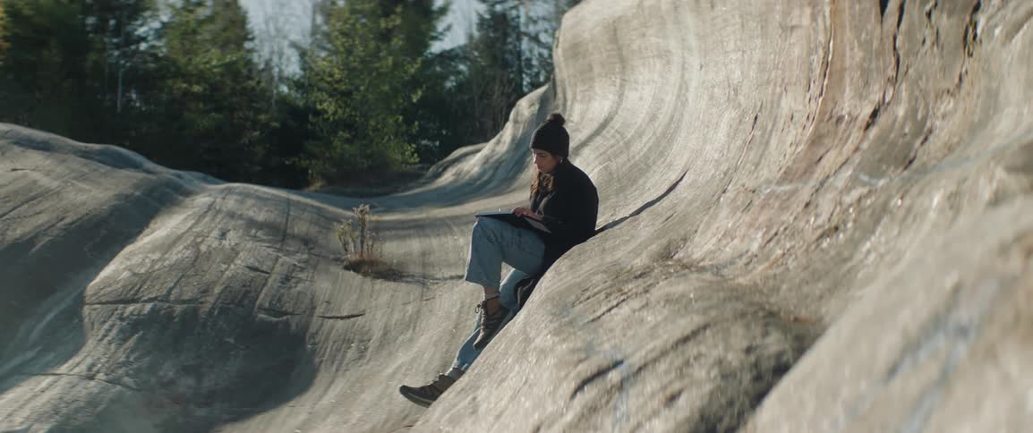A girl sitting on a rock observing the landscape