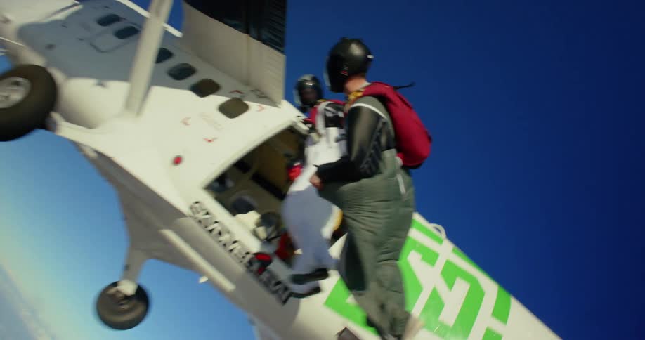 Three people jump out of an airplane wearing wingsuits