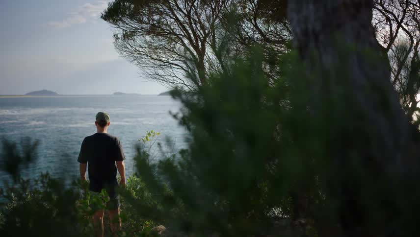 View of a mans back on a hill looking out at the sea
