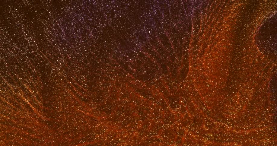 Fine particles glitter and sparkle while moving through reddish mixture