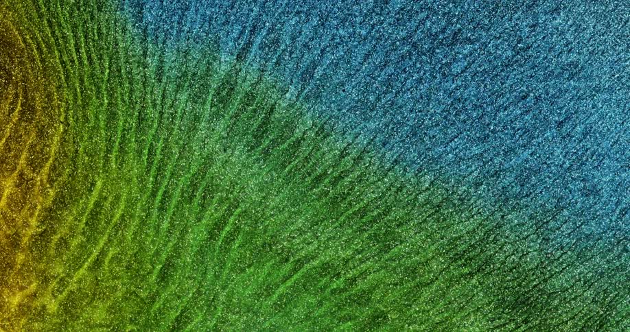 Extreme closeup of a glowing abstract fluid in shades of green blue and yellow
