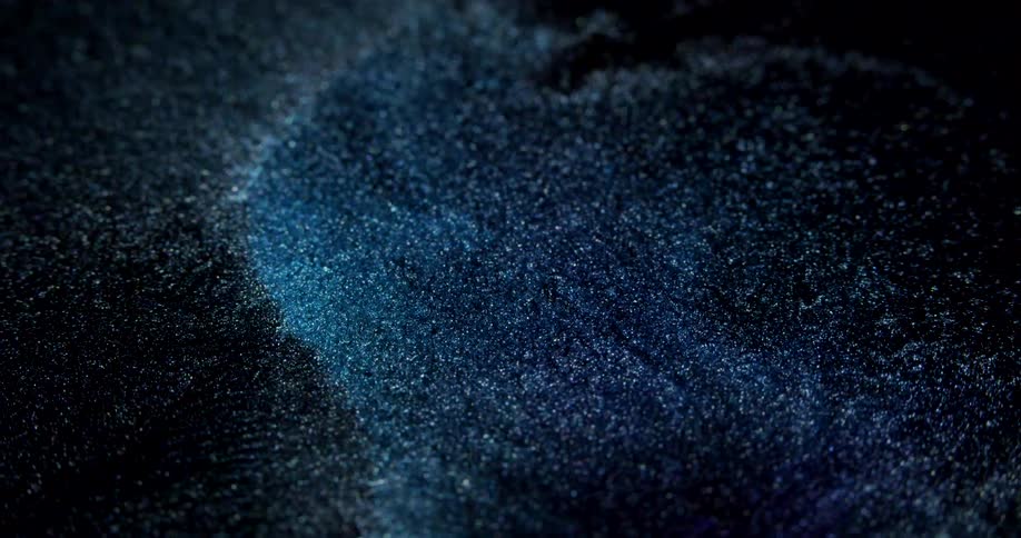 Several blue particles on a black surface