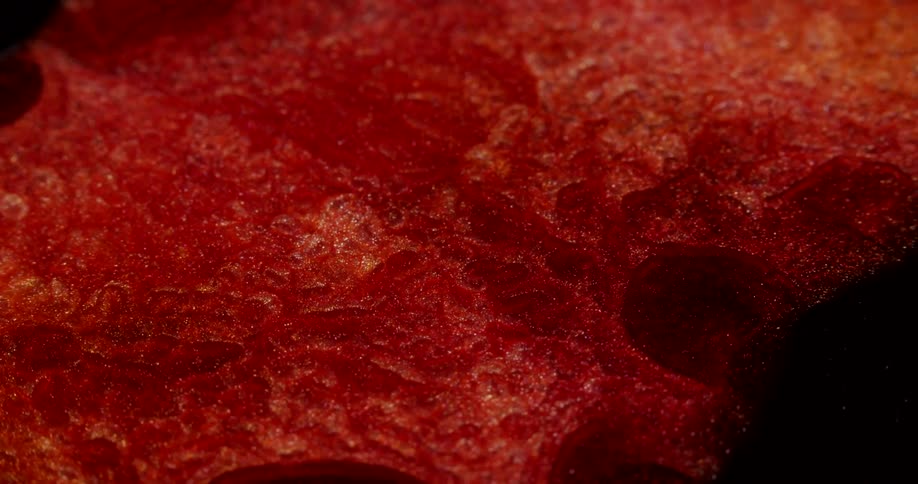 Metallic particles glitter in slowly flowing orange and red mixture