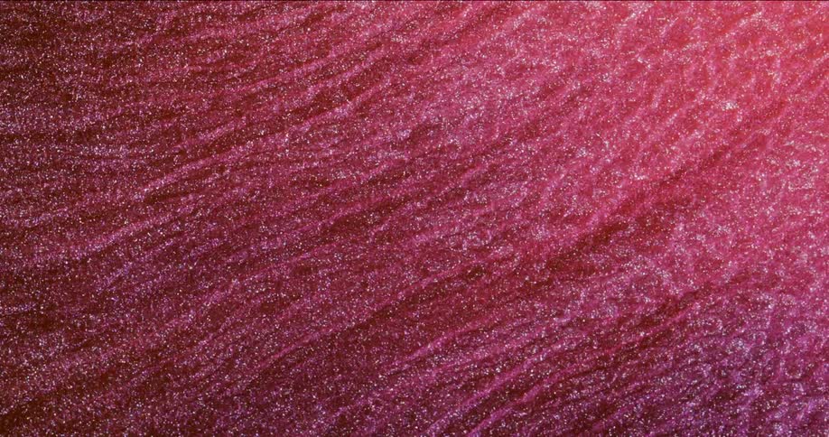 Metallic particles glitter in flowing red striated mixture