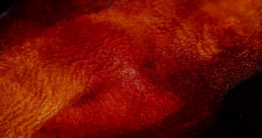 Closeup of a shiny red aqueous fluid in slow motion