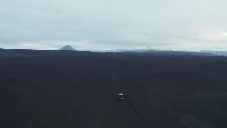 A car traveling through a desert landscape during a cloudy day