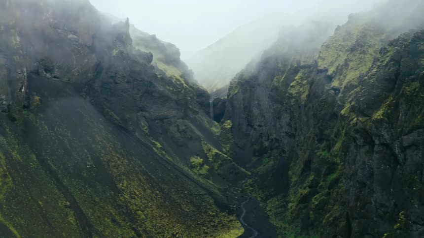 Aerial of a valley between rocky mountain ranges during cloudy days