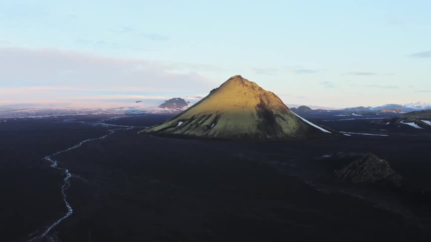Aerial panorama of a mountain amidst black terrain under a morning sky in winter