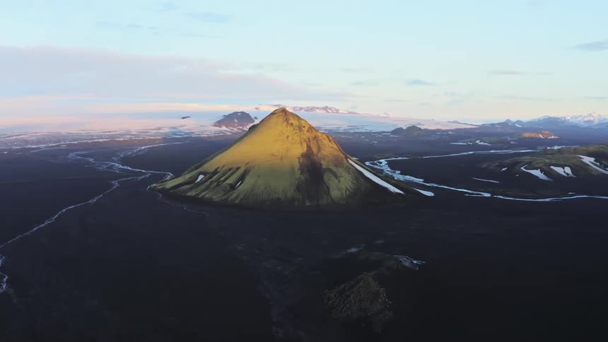 Aerial panorama of an inactive volcano amidst black terrain under a morning sky in winter