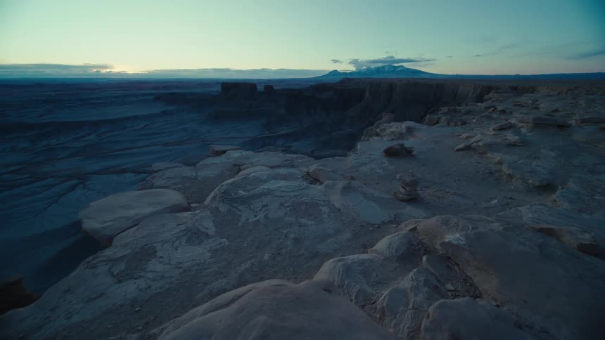 Sun rises on horizon shining across arid land of mesas and plateaus