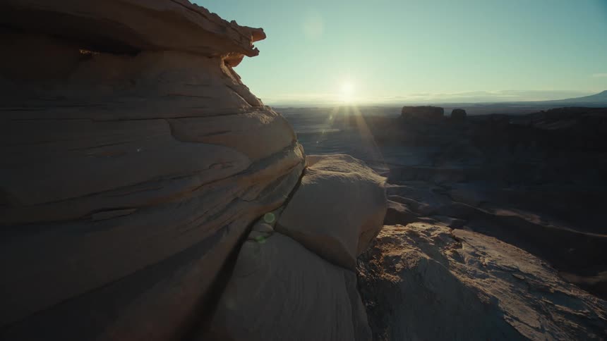Sun shines across arid land surrounding mesas and plateaus