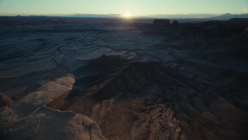 Panorama of a rocky terrain amidst valleys with the sun rising on the horizon
