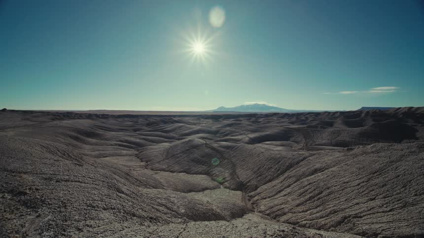 A region with rock formations and cracks in the rocks and in the sky the sun is shining brightly