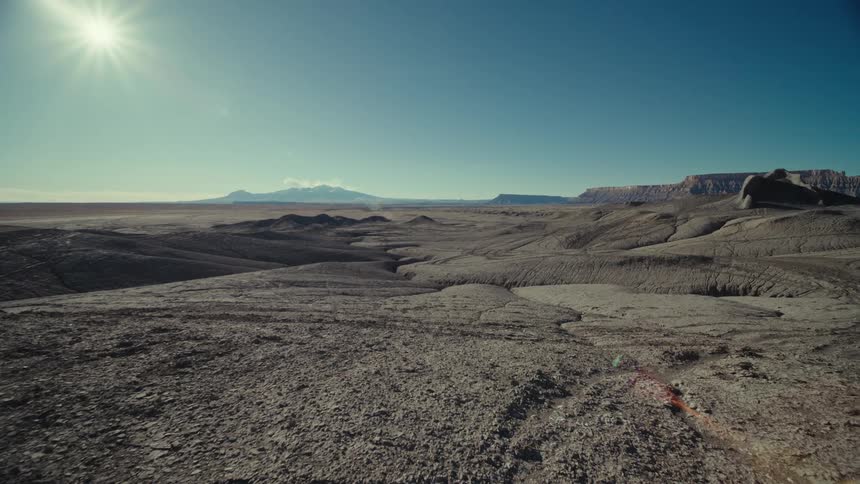 A view of the desert badlands with the sun high in the sky
