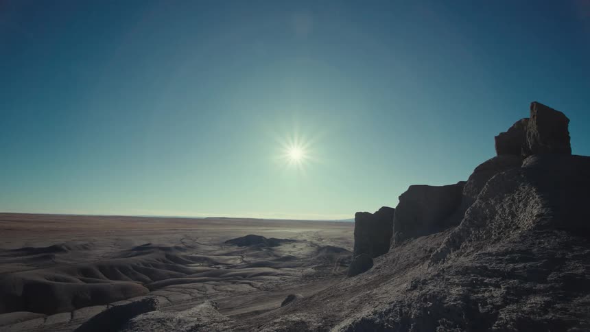 Rock formations sun in blue sky above horizon