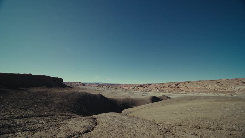 A stretch of rocky desert with a hole in the ground at the center
