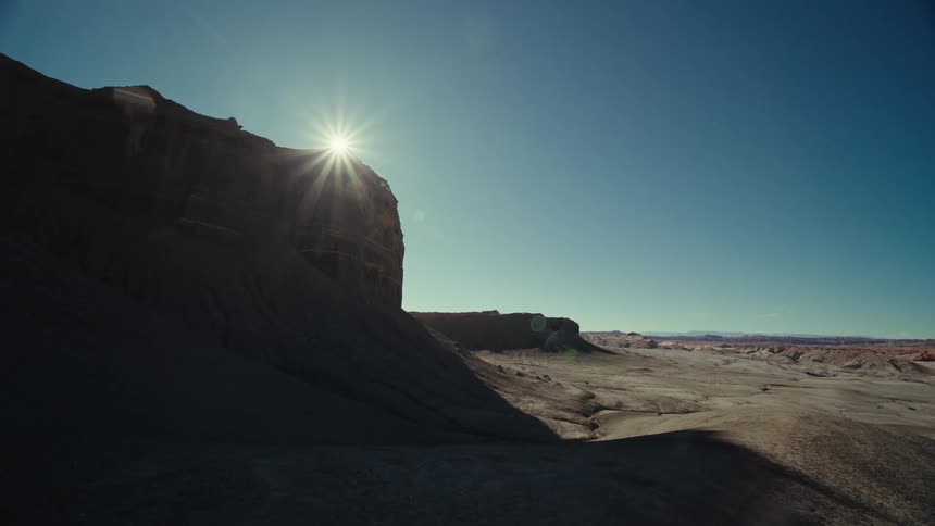 A view of canyons out in the desert with sun in the distance