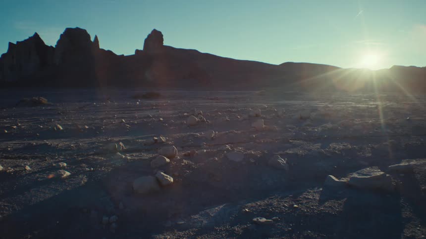 Panorama of a rocky and desert terrain with a valley on the horizon and the sun reflecting