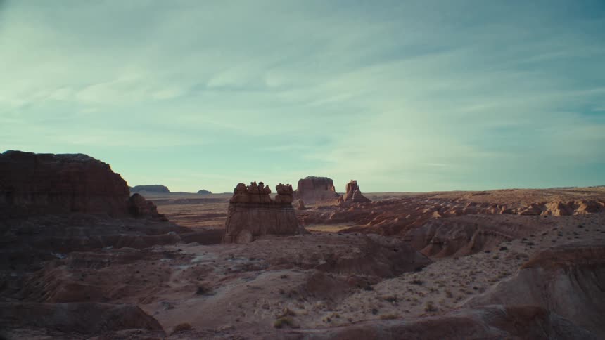 Light clouds cover arid terrain of plateaus and mesas