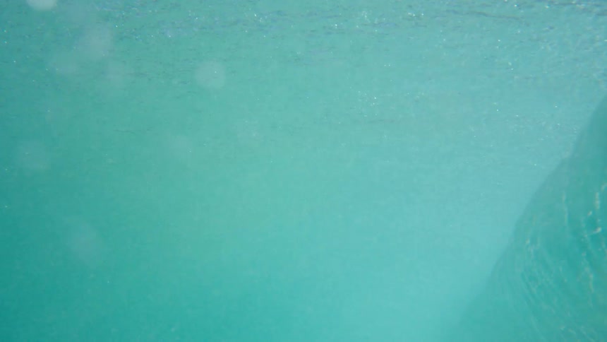 Wave of aquamarine water crashes stirring up sandy seafloor near shore