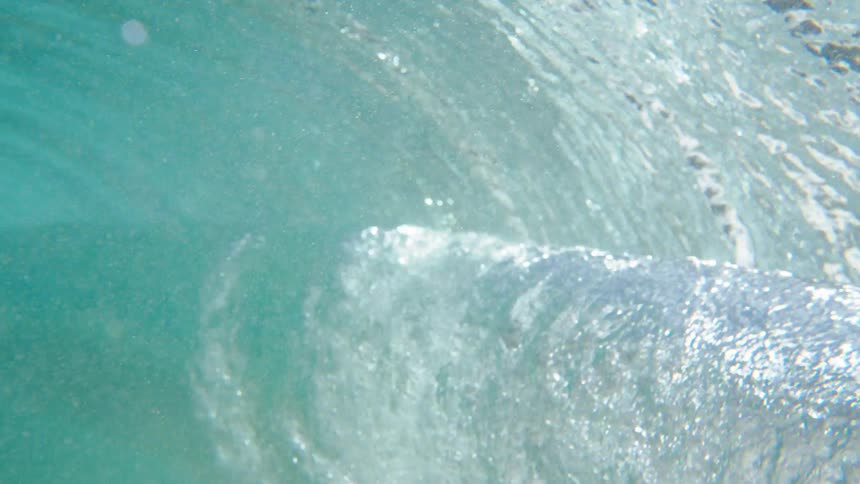View from inside the sea with a wave passing in turquoise blue water with sunlight reflection