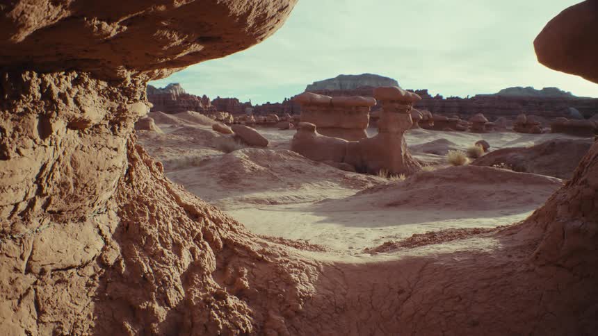 View of geological rocks amidst a desert terrain with canyons in the background