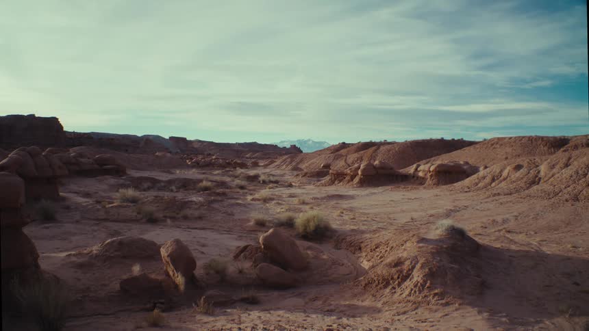 Desert with scant tumbleweeds on a cloudy day with blue sky peeking through