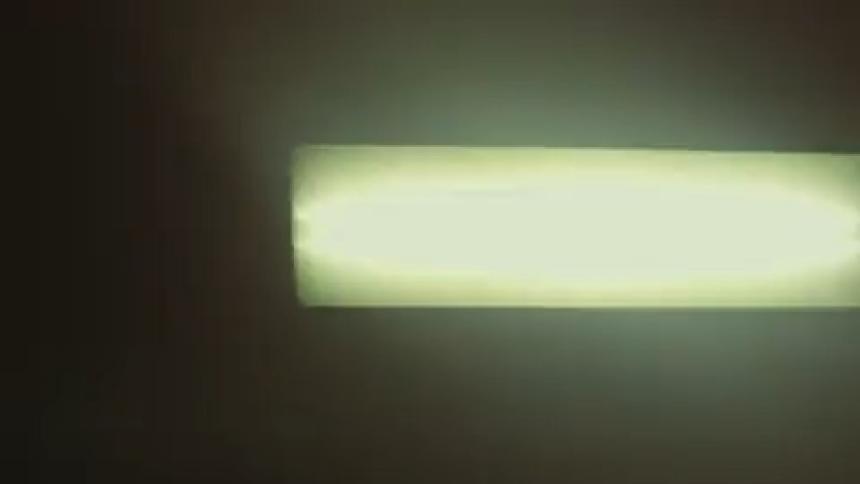 Closeup of a lamp inside a subway with a passing train generating reflections