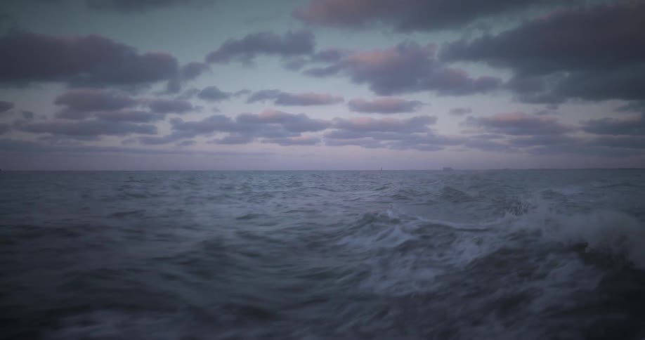 A cloudy evening in the ocean with waves caused by boat