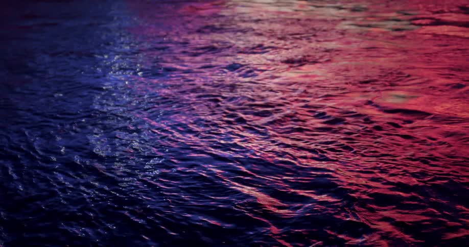 Blue and purple lights reflected on a body of water at night