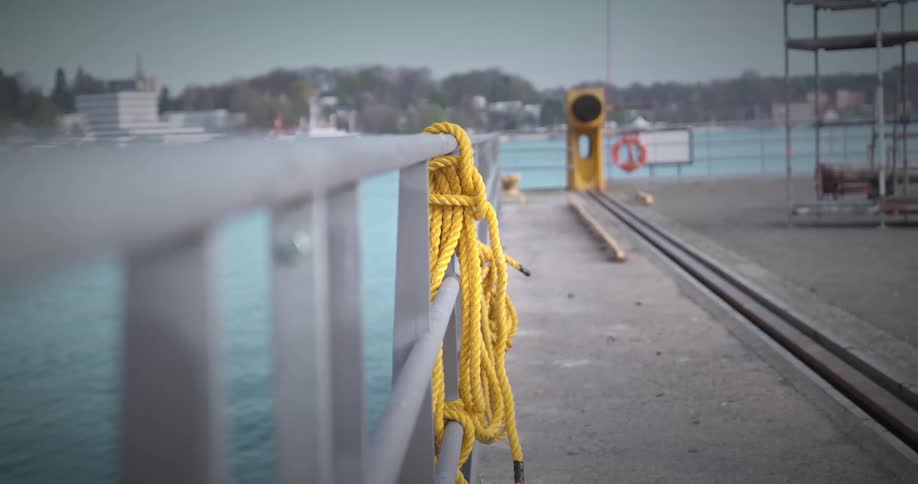 A yellow rope entwined in a metal handrail and next to a sea