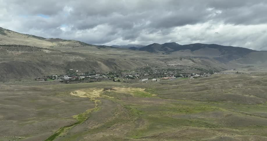 Panoramic view of a village in the background with a mountain range around it on a cloudy day