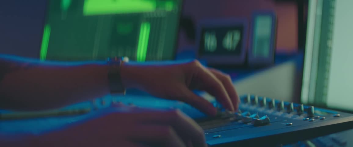 Technician manipulates audio mixer control panel in recording studio