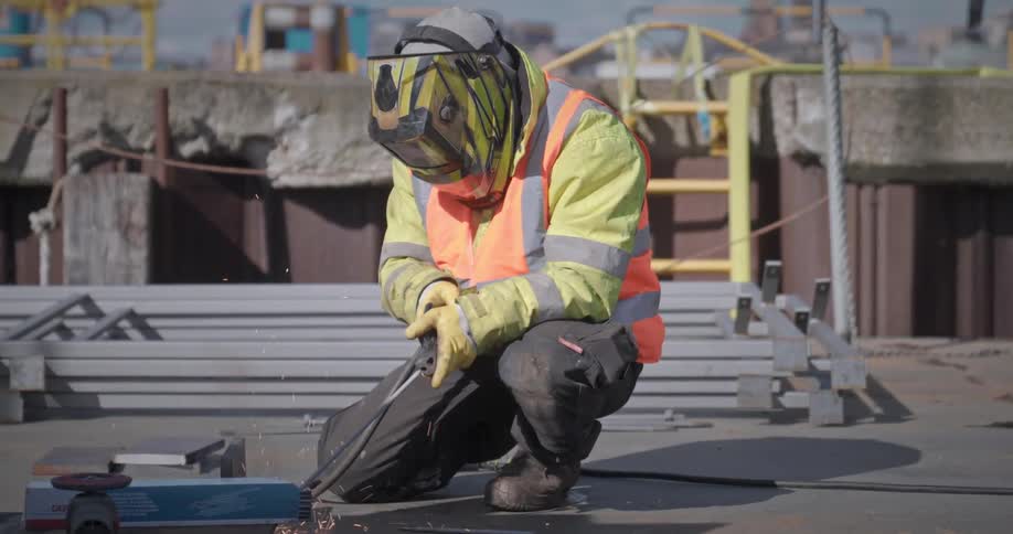 Man with helmet and protective clothing adjusting a welding device