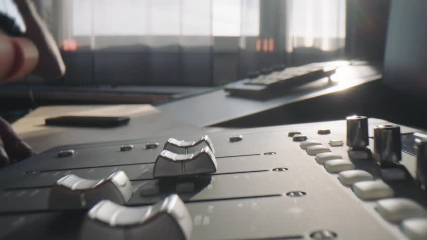 Closeup of a mans hands adjusting the music mixer