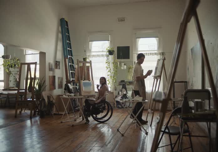 A couple of artists painting with oils over canvas in a studio
