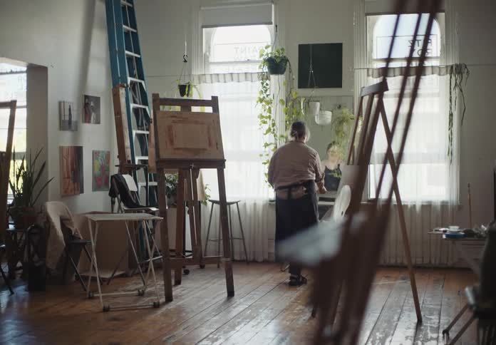 Female artist moves table toward center of art studio